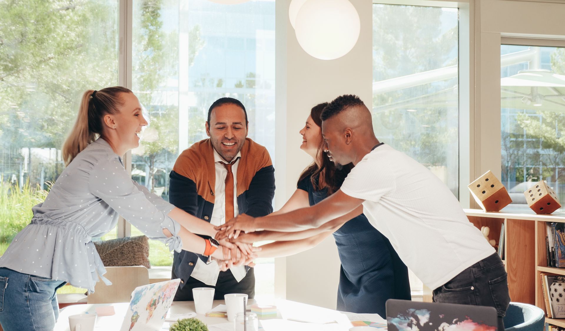 Diverse group of business professionals joining hands in a bright modern office, representing trust and collaboration